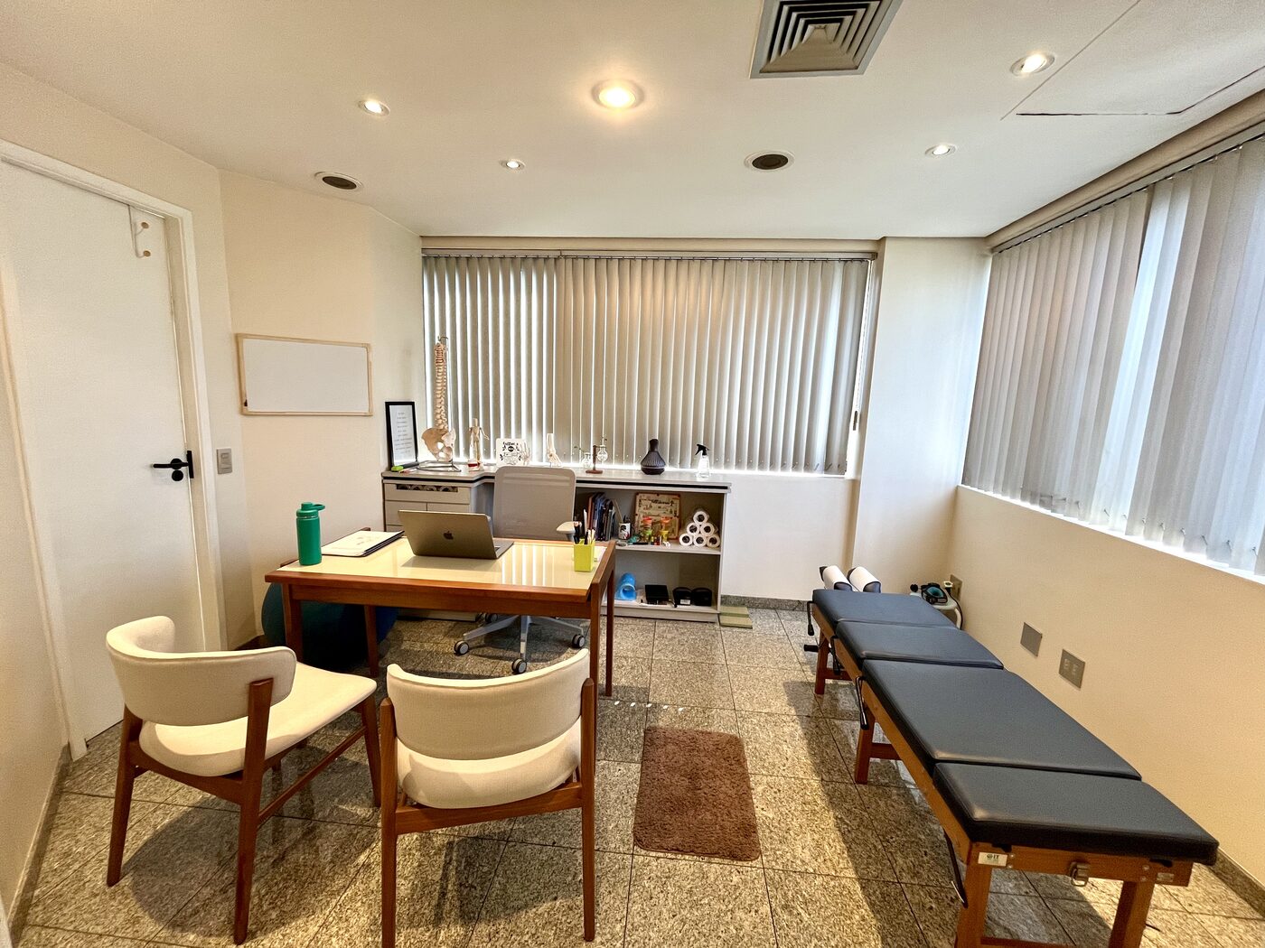 Sala de atendimento do consultório Rubens Watanabe Quiropraxia, São Paulo, com maca e modelo de coluna vertebral